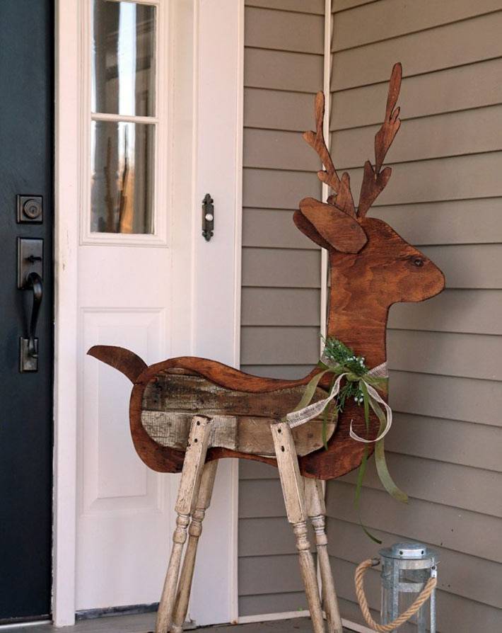 деревянный олень как новогоднее украшение при входе в дом