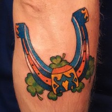 Татуировка на руке парня - подкова и клевер