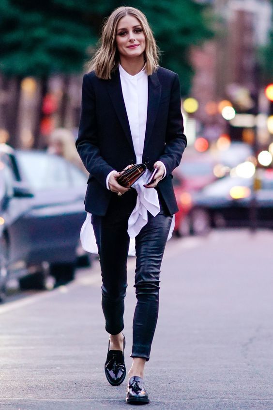 На девушке черный пиджак, белая блуза с бантом, кожаные черные брюки и лаковые лоферы.